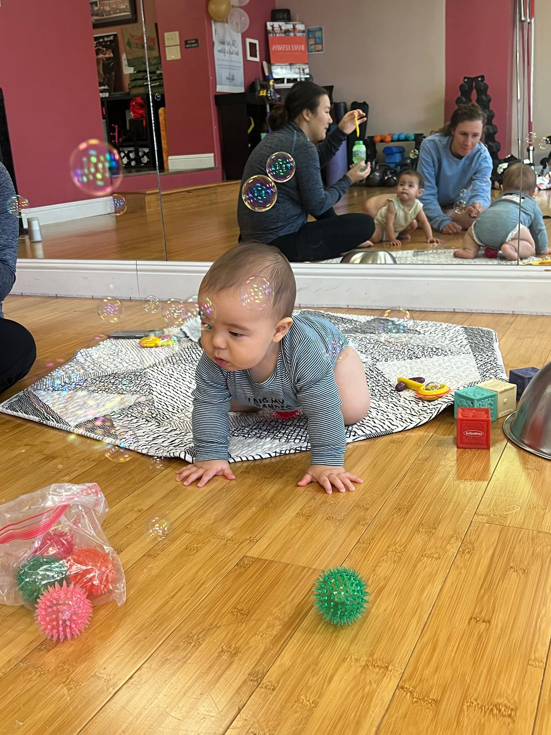 baby crawling on the floor with toys and bubbles