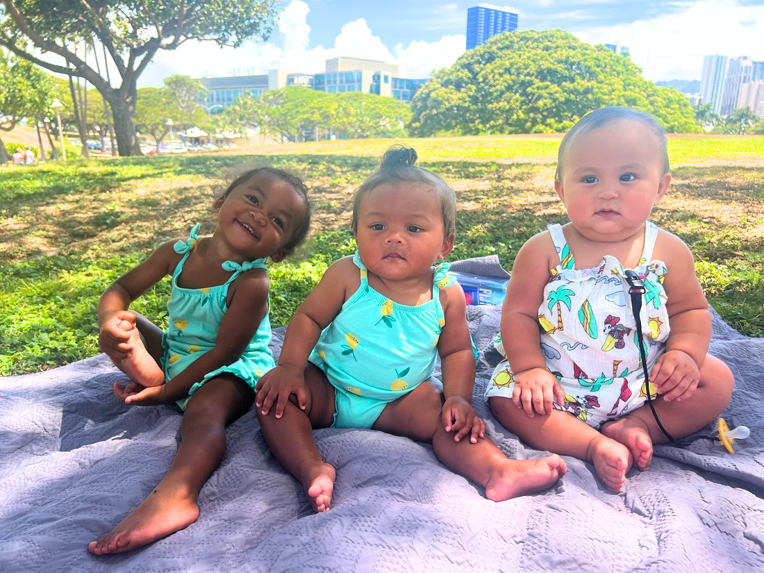 three babies sitting together in the park