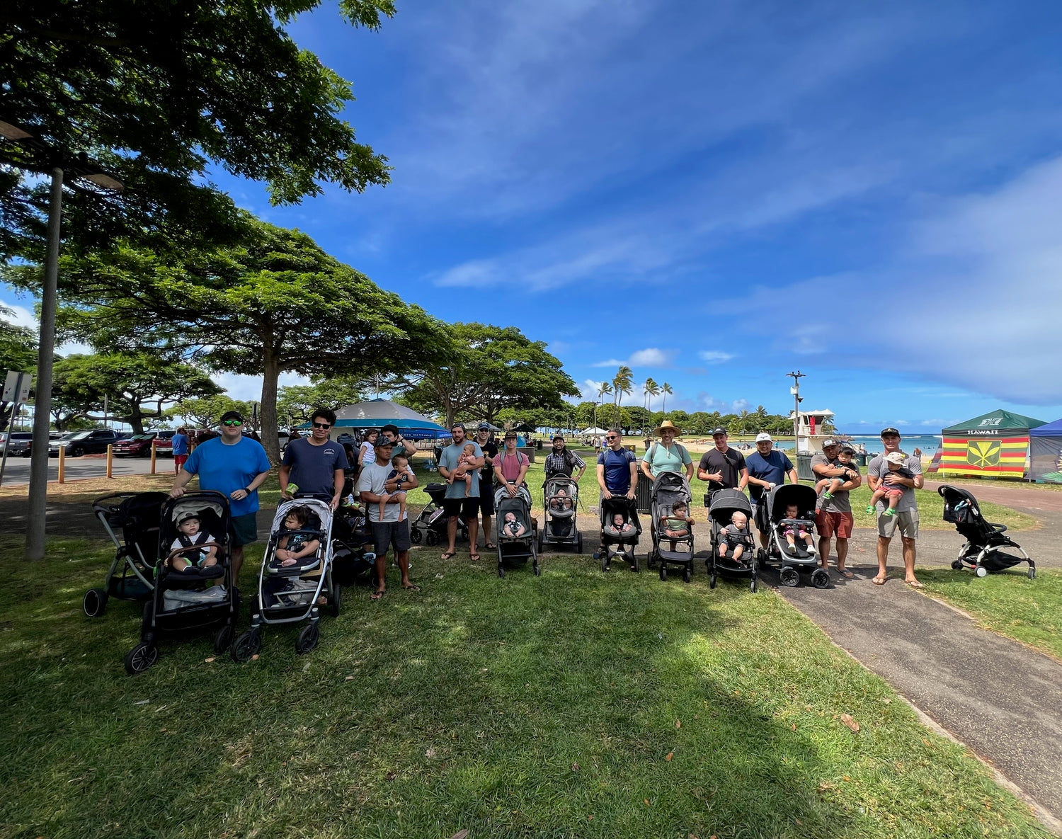 Group of hawaii dads with strollers in a park on a sunny day