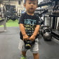 Child holding a small black weight in a gym setting