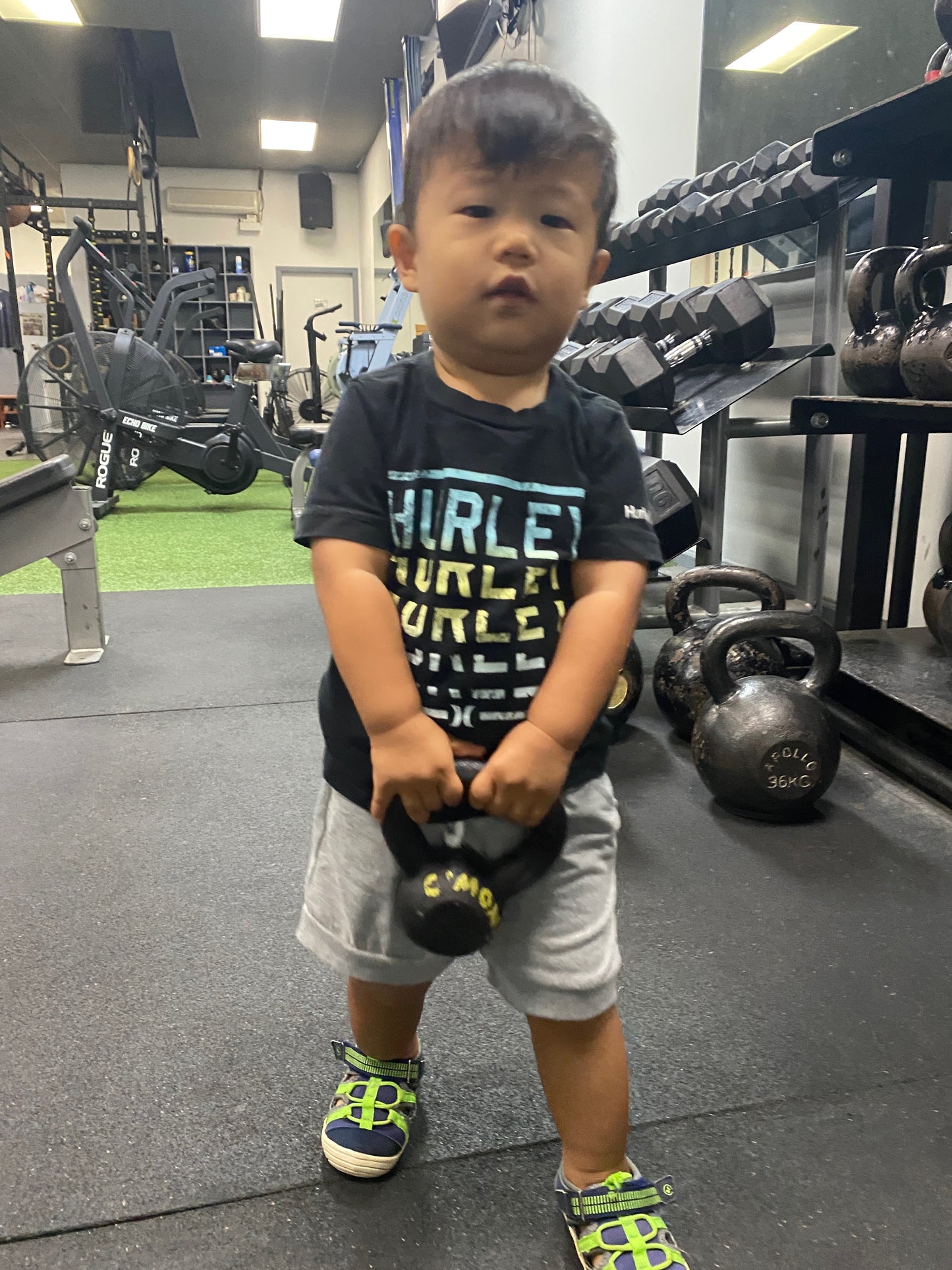 Child holding a small black weight in a gym setting