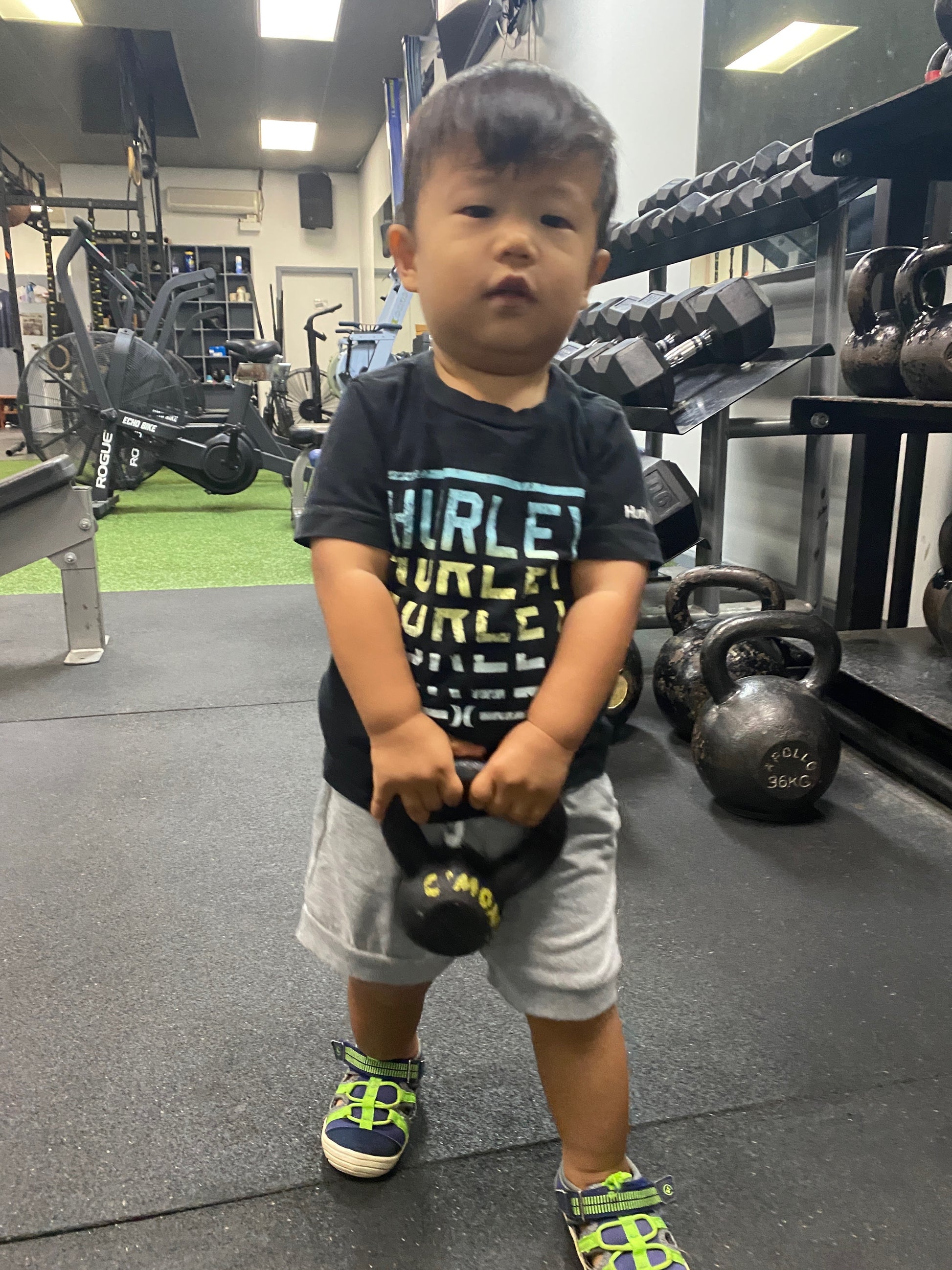 Child holding a small black weight in a gym setting