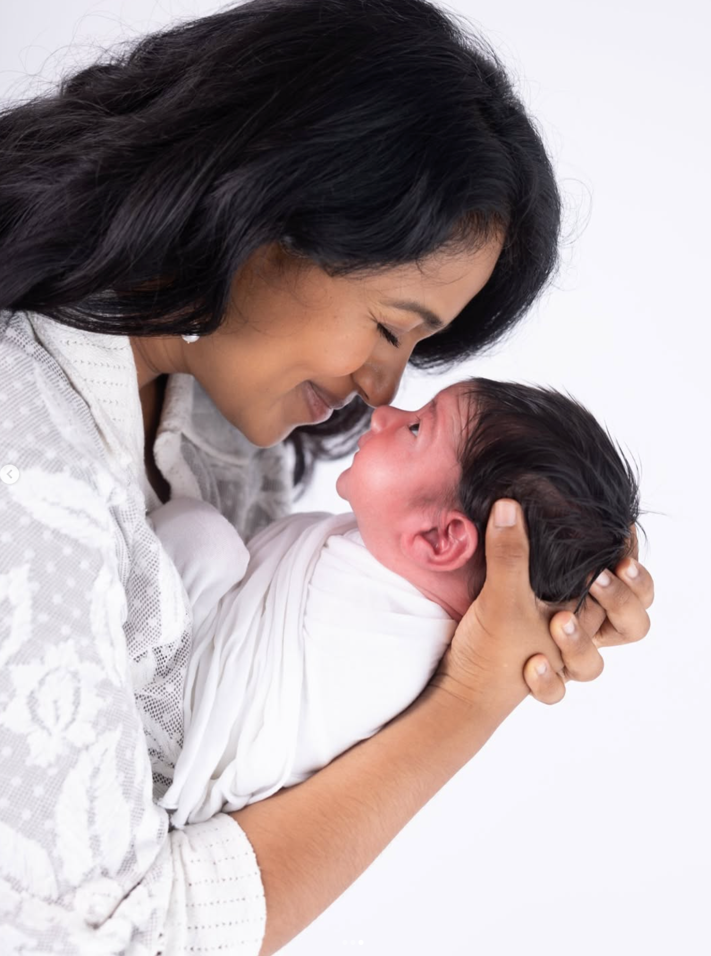 Woman holding a newborn baby against a white background