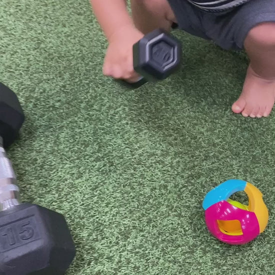 a toddler boy playing with a rattle at the gym