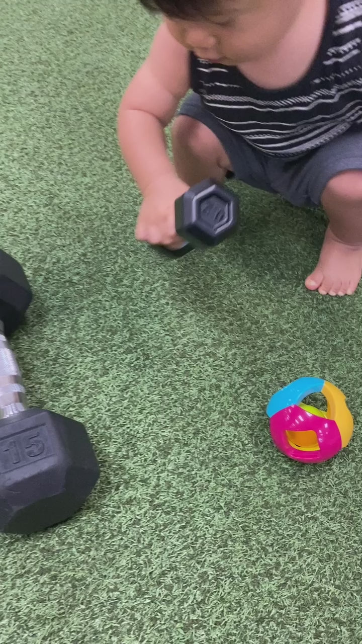 a toddler boy playing with a rattle at the gym