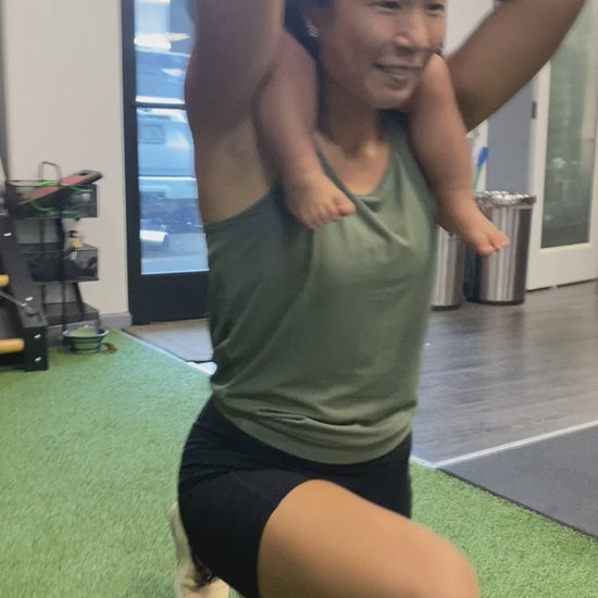 a mom doing lunges at the gym with her toddler on her shoulders
