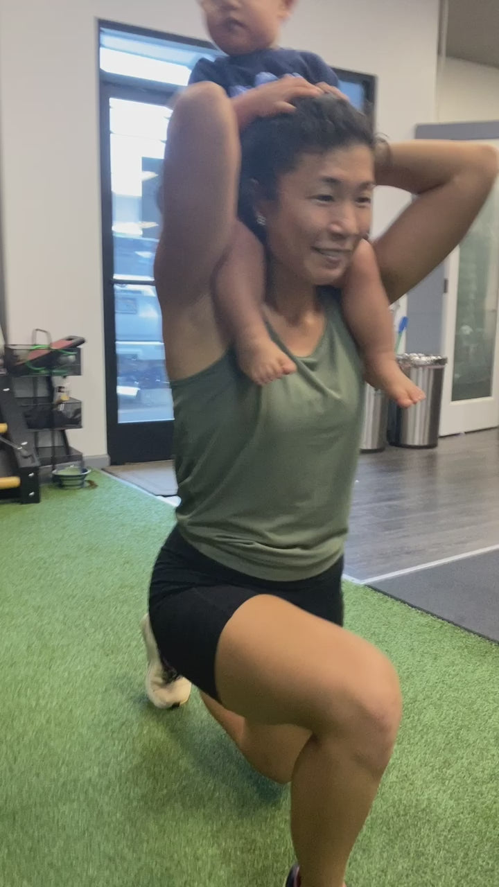 a mom doing lunges at the gym with her toddler on her shoulders